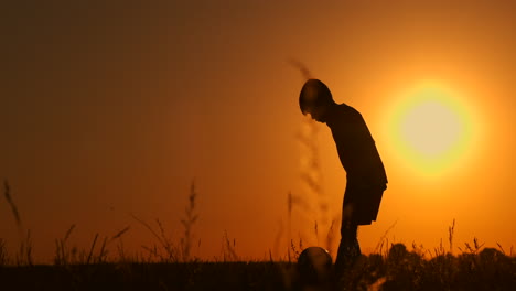 Silhouette-Eines-Jungen,-Der-Bei-Sonnenuntergang-Fußball-Spielt.-Ein-Junge-Jongliert-Bei-Sonnenuntergang-Auf-Dem-Feld-Mit-Einem-Ball.